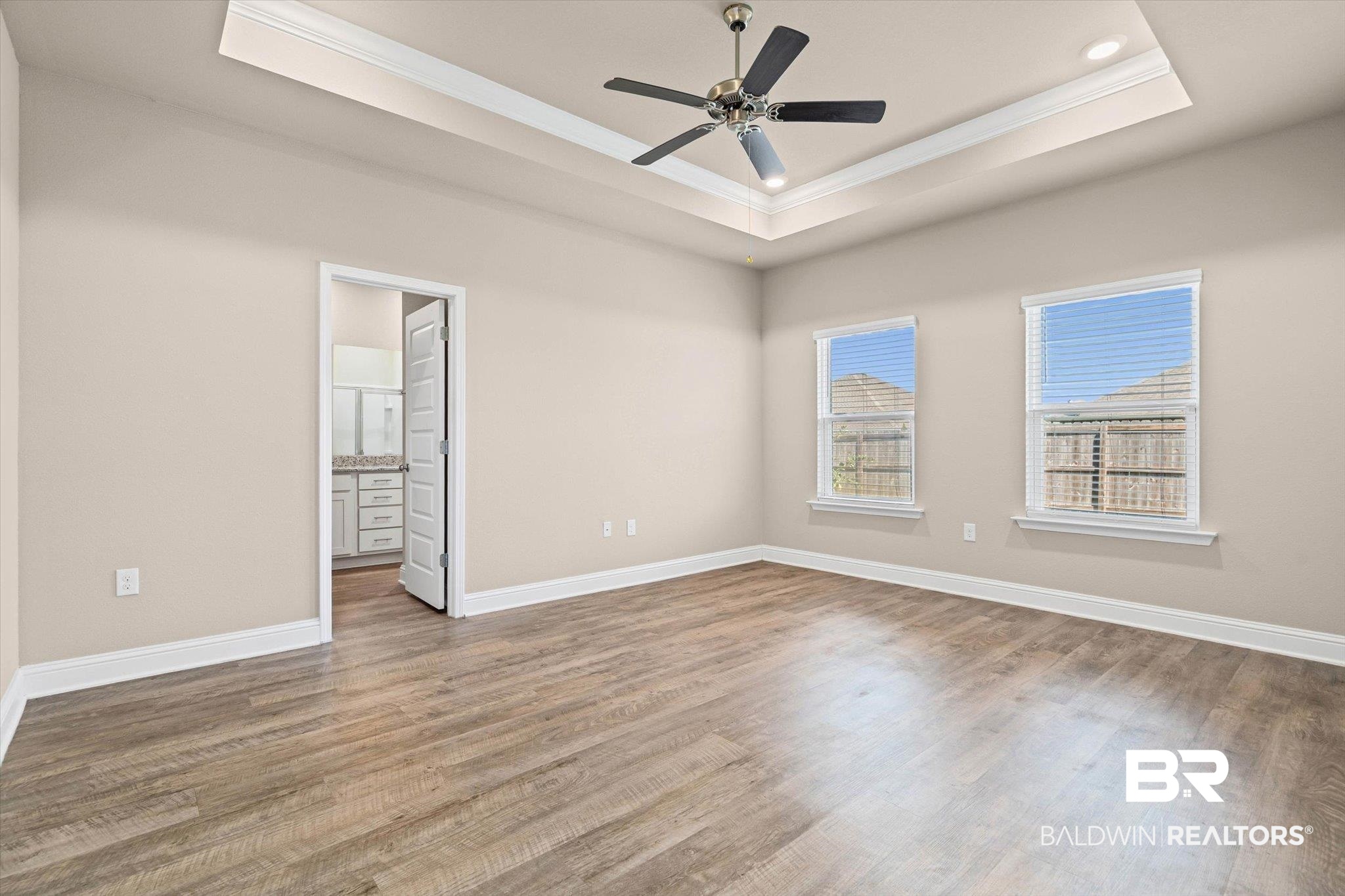 22976 Lieutenant Avenue Foley, AL 36535 - Photo 9 of 30 Unfurnished bedroom featuring a tray ceiling, light wood-style floors, ornamental molding, ensuite bathroom, and a ceiling fan