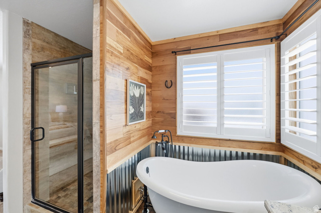 3732 Campbell Road Tooele, UT 84074 - Photo 30 of 69 Freestanding soaking tub with dark bronze fixtures, wood-paneled walls, and white plantation shutters