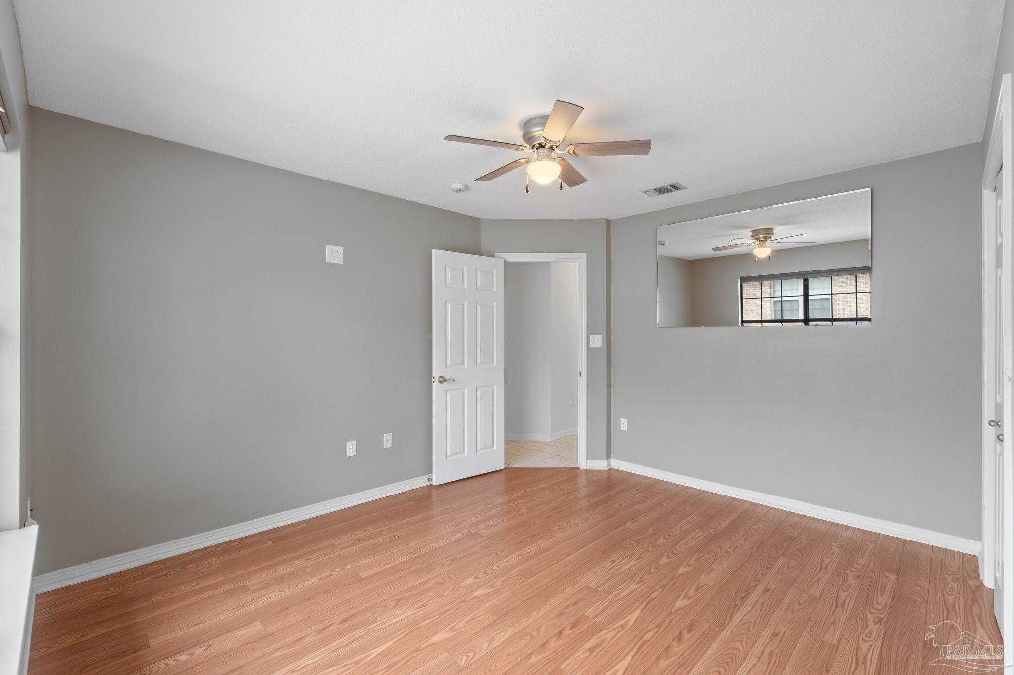 2640 Masters Boulevard Navarre, FL 32566 - Photo 16 of 40 an empty room with wooden floor fan and windows