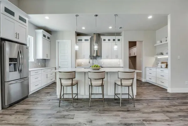 a kitchen with stainless steel appliances kitchen island granite countertop a dining table chairs refrigerator and sink