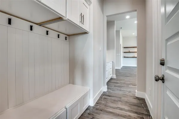 a hallway with white doors wooden floor and stairs