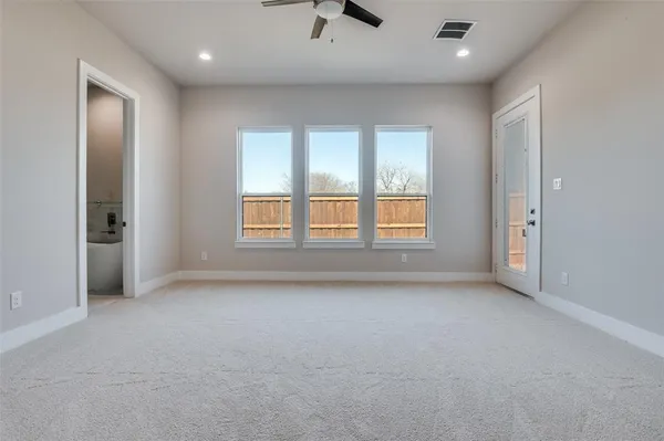 an empty room with chandelier fan and windows