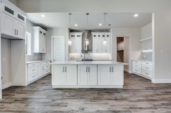 a large white kitchen with kitchen island a sink a center island stainless steel appliances and cabinets