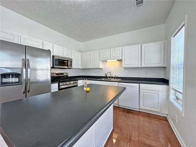 a kitchen with cabinets stainless steel appliances a sink and a microwave
