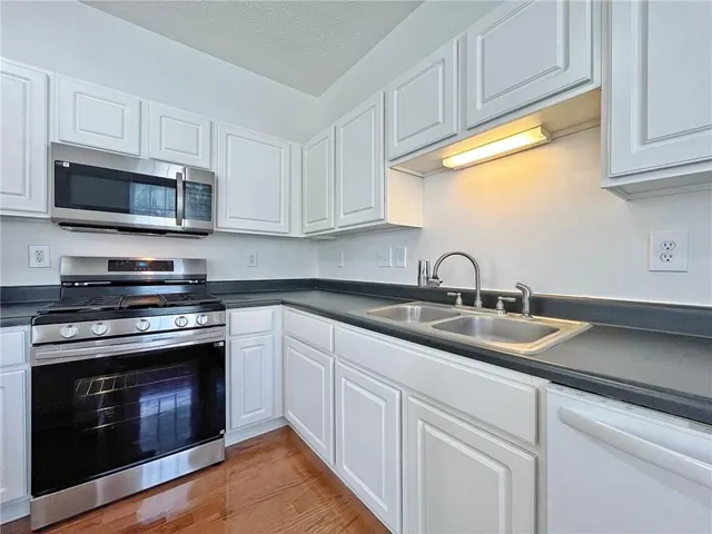 a kitchen with stainless steel appliances granite countertop a sink a stove a microwave a refrigerator a sink and dishwasher