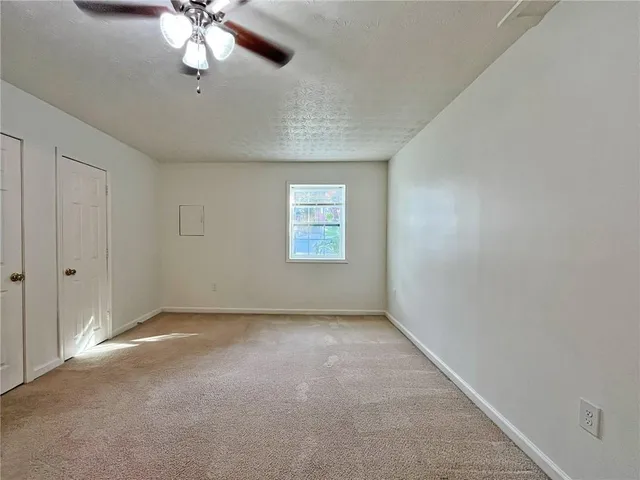 an empty room with a chandelier fan and windows