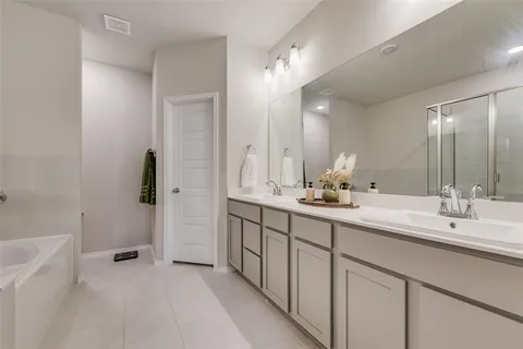 a bathroom with a double vanity sink a mirror and a bathtub