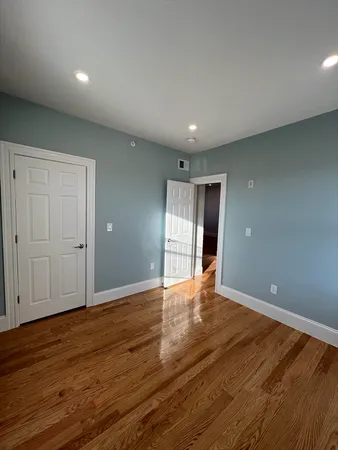 a view of an empty room with wooden floor and closet