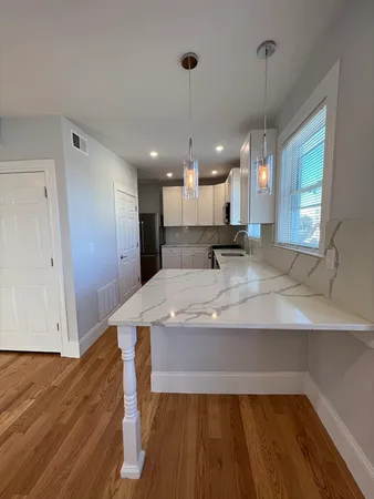 a view of a kitchen with kitchen island a sink wooden floor and a window
