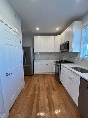 a large kitchen with wooden floors and stainless steel appliances
