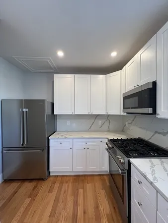 a kitchen with granite countertop a refrigerator and a stove top oven