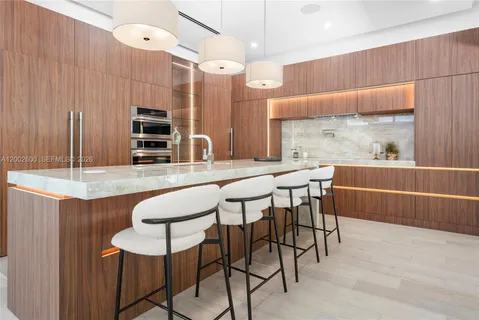 a kitchen with stainless steel appliances kitchen island granite countertop a table chairs and a refrigerator