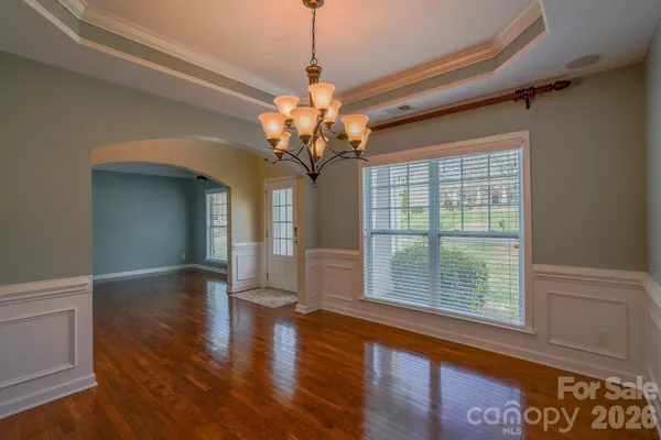 a view of a room with wooden floor chandelier and windows
