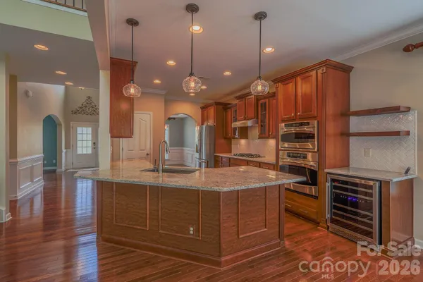 a large kitchen with kitchen island a stove a sink a refrigerator and chairs