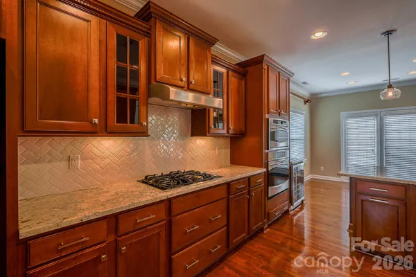 a kitchen with stainless steel appliances granite countertop a stove a sink and dishwasher cabinets with wooden floor