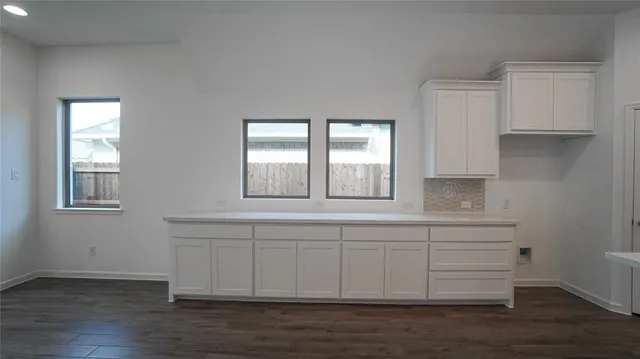 an empty room with chandelier fan and windows