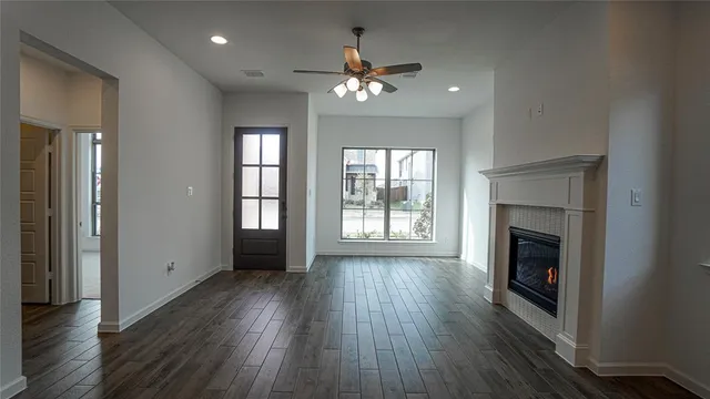 an empty room with wooden floor fireplace and windows