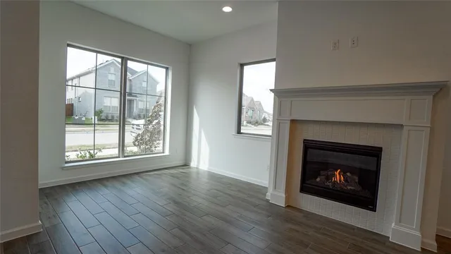 an empty room with wooden floor fireplace and windows