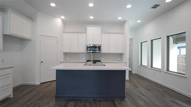 a kitchen with granite countertop a sink a stove and cabinets