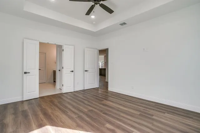 a view of empty room with wooden floor and fan
