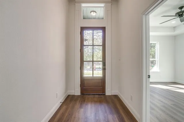 a view of a hallway with wooden floor and a window