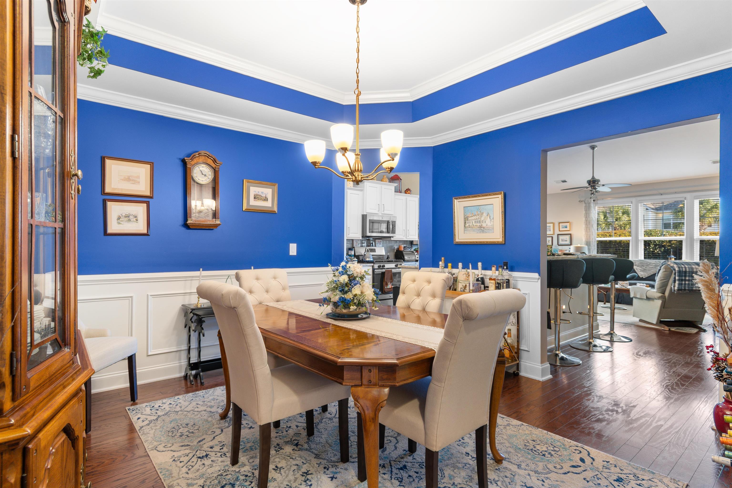 5459 Elba Way, Unit 1501 Myrtle Beach, SC 29579 - Photo 12 of 31 Dining area featuring a wainscoted wall, dark wood-style floors, a chandelier, crown molding, and a decorative wall
