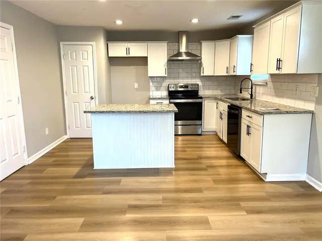 a kitchen with stainless steel appliances granite countertop a stove a sink dishwasher and a refrigerator with wooden floor