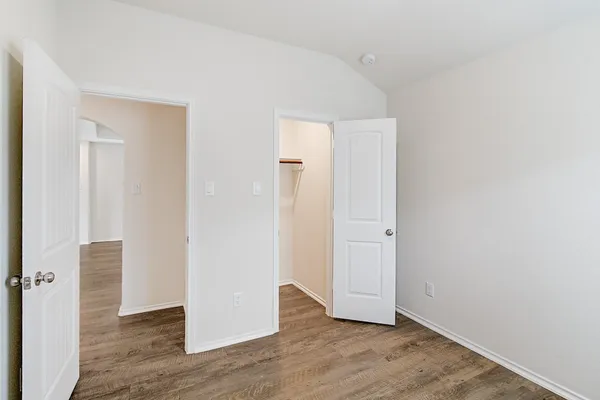 an empty room with wooden floor & windows