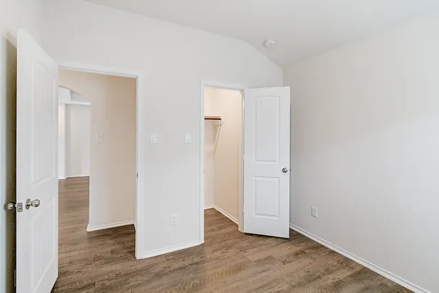 an empty room with wooden floor & windows