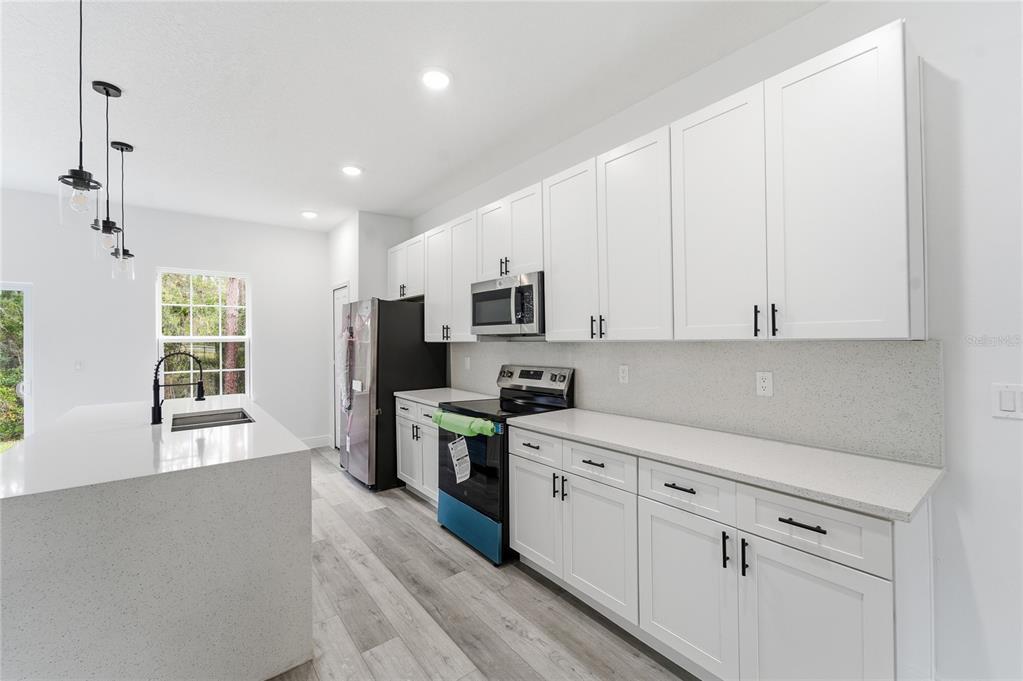 6312 Southwest 144th Lane Road Ocala, FL 34473 - Photo 11 of 32 a kitchen with granite countertop white cabinets and stainless steel appliances