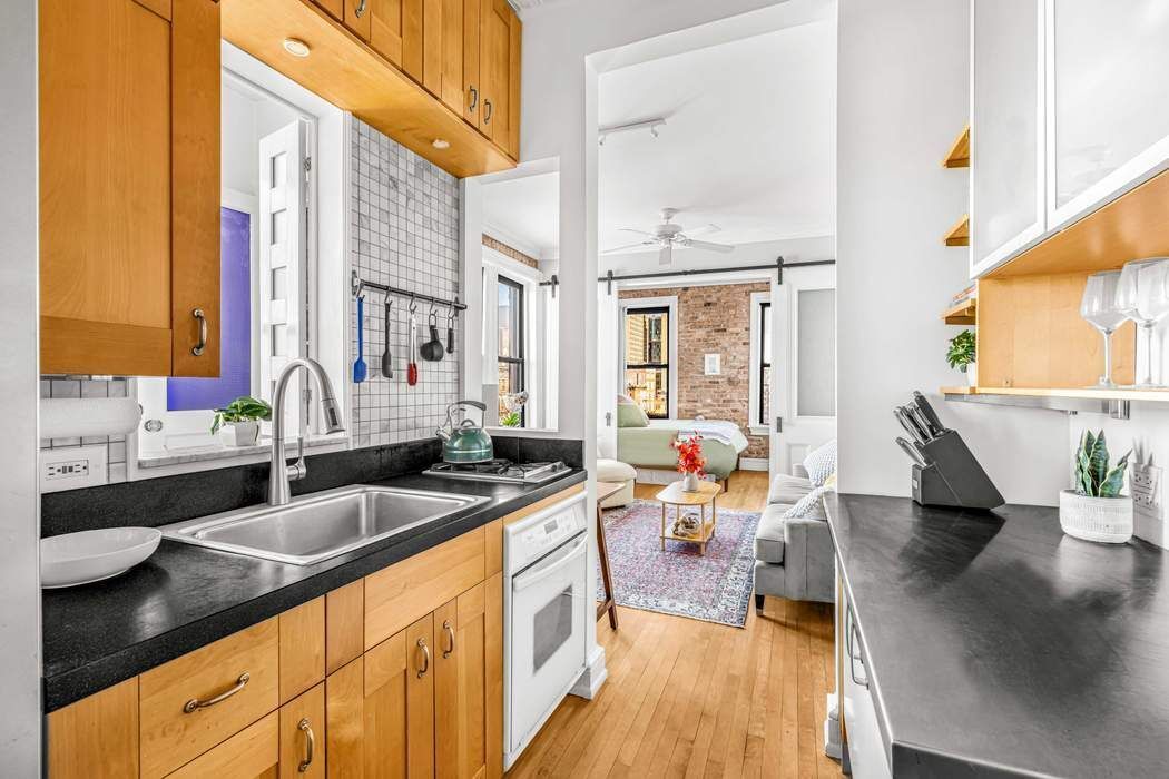 64 MacDougal Street, Unit 22 Manhattan, NY 10012 - Photo 2 of 13 a kitchen with stainless steel appliances granite countertop a sink dishwasher a stove a dining table and chairs with wooden floor