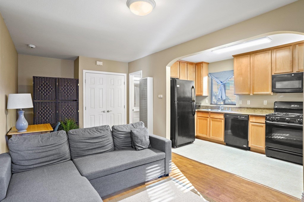 a large living room with stainless steel appliances furniture and a kitchen view