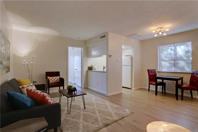 a living room with furniture and a dining table with kitchen appliances