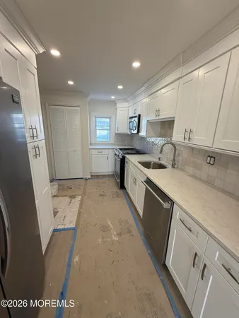 a large kitchen with stainless steel appliances granite countertop a sink a stove a washer dryer and a refrigerator