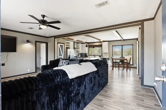 a living room with stainless steel appliances furniture a fireplace and a flat screen tv