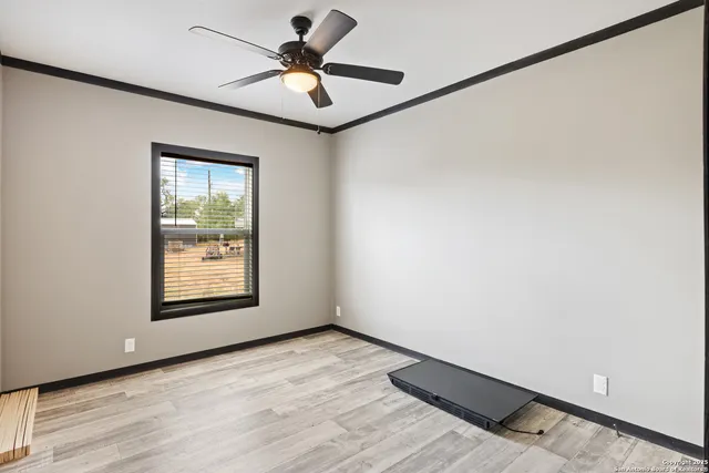 a view of an empty room with a window and a ceiling fan