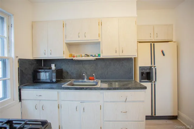 a kitchen with stainless steel appliances granite countertop a refrigerator and white cabinets