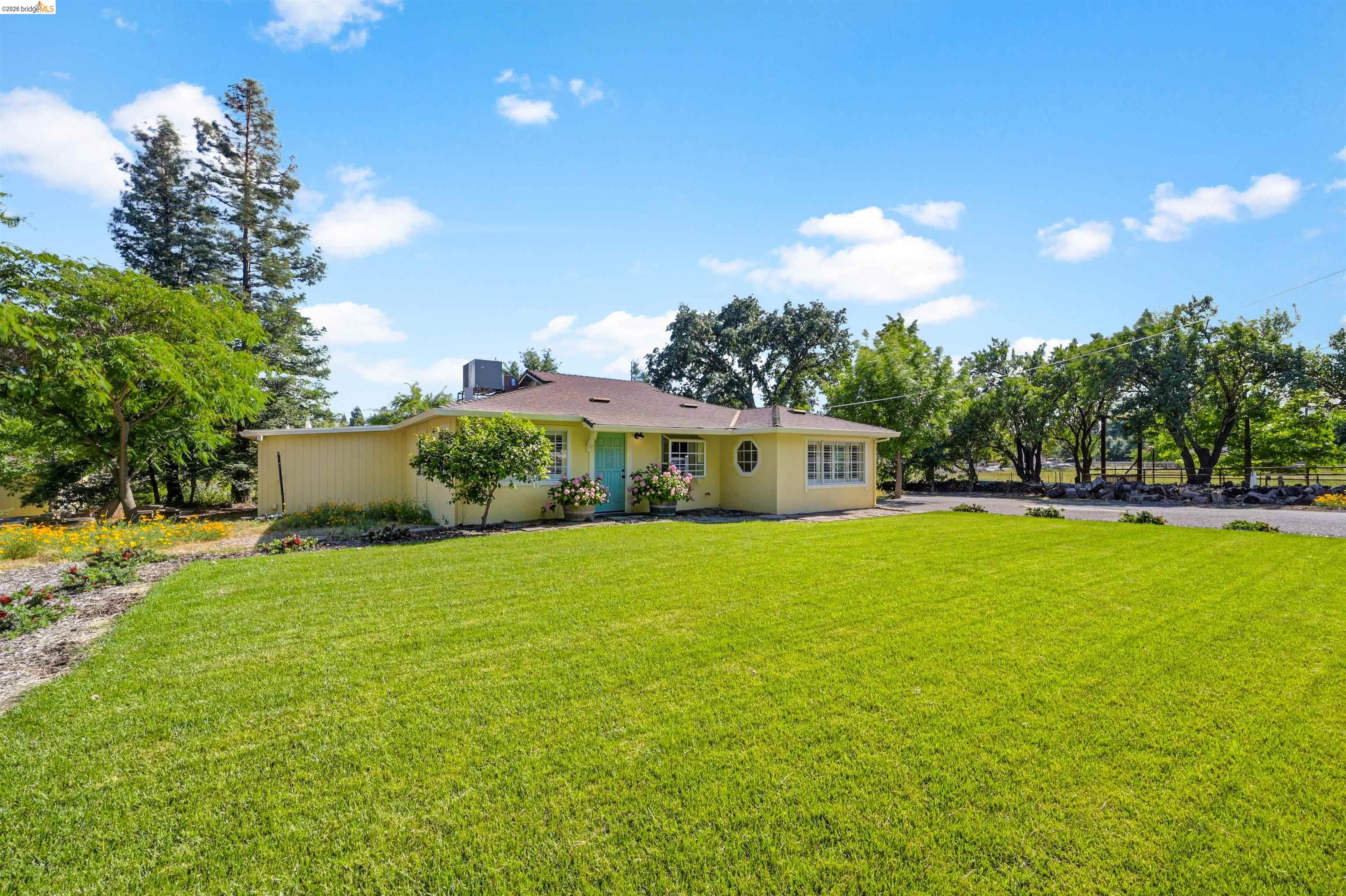 10474 Sheldon Road Elk Grove, CA 95624 - Photo 6 of 83 Ranch-style residence featuring a pale yellow exterior, a turquoise entry door, and a brown shingle roof
