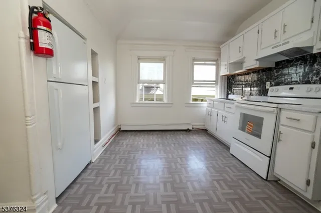 a kitchen with granite countertop a stove and white cabinets