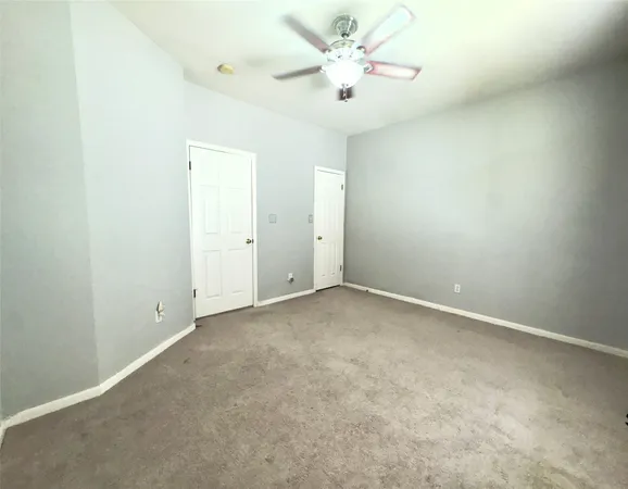 an empty room with a bathroom and a ceiling fan