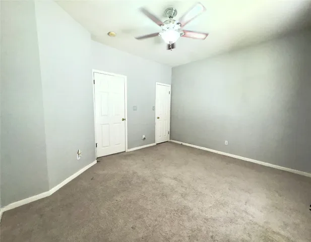 an empty room with a chandelier fan and windows