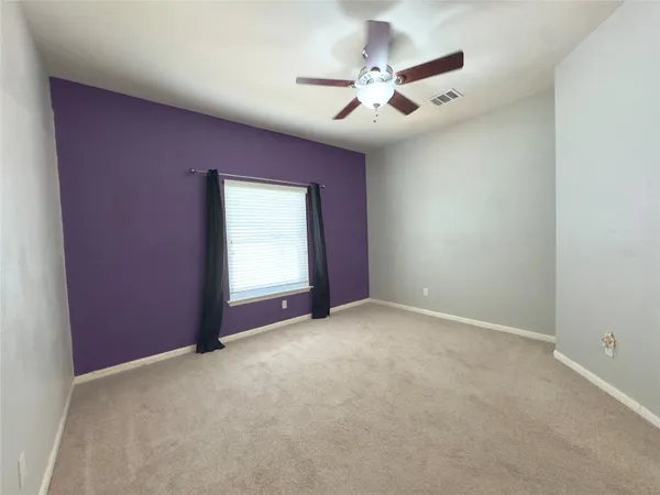 an empty room with windows and fan