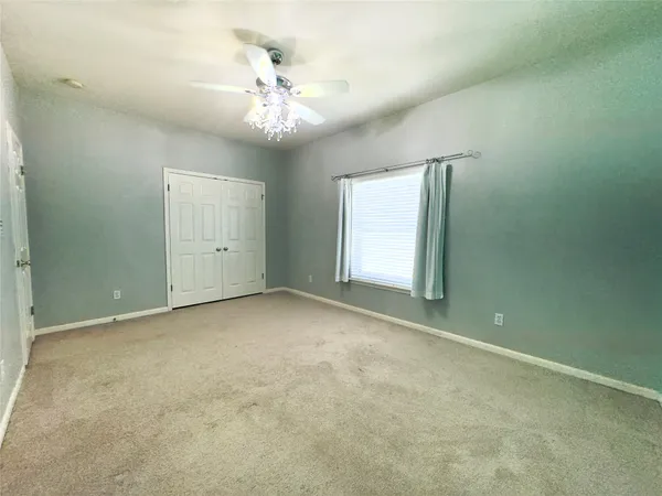an empty room with chandelier fan and windows