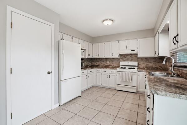 1547 West 99th Avenue Crown Point, IN 46307 - Photo 4 of 21 a kitchen with white cabinets and white appliances