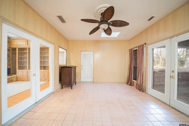 an empty room with windows and ceiling fan