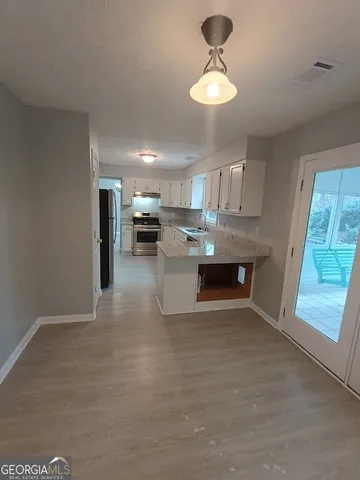 a living room with stainless steel appliances granite countertop furniture and a chandelier