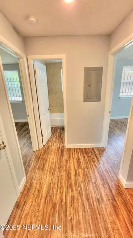 a view of empty room with wooden floor and fan