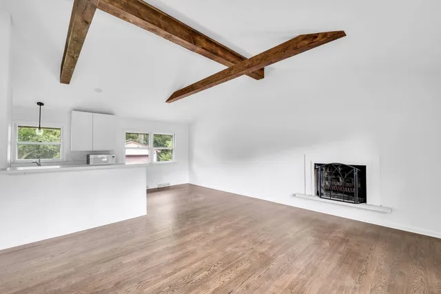 a view of empty room with wooden floor and window