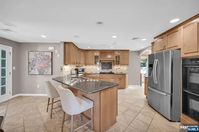 a kitchen with stainless steel appliances granite countertop a refrigerator a sink a stove a dining table and chairs