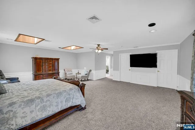 a spacious bedroom with a bed and a flat screen tv